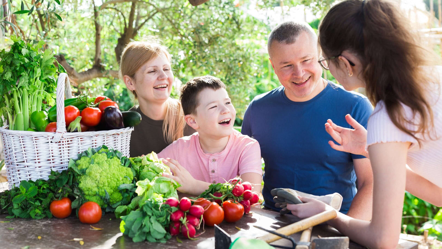 Family members smiling as they gather around a table adorned with freshly harvested vegetables